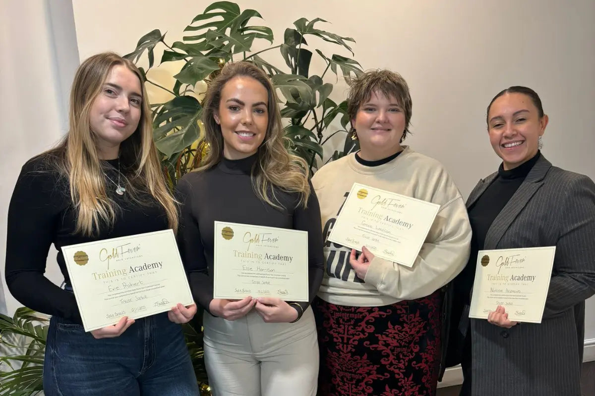 Four smiling stylists from Trevor Sorbie salons proudly displaying their Gold Fever hair extension certifications.